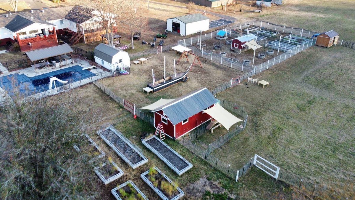Aerial view of Amen Farms, with the pool, gardens, and red barns tucked into the Woodville, Alabama hills